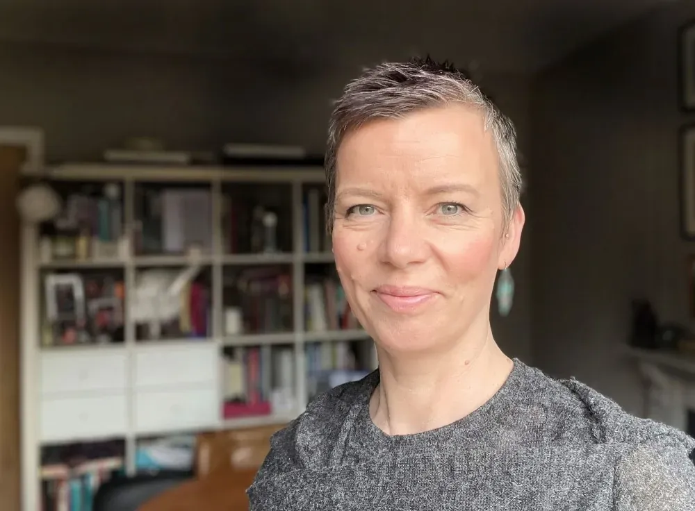 Portrait of a smiling woman in front of a bookshelf