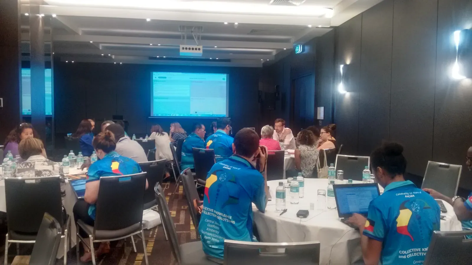 Participants at round tables using laptops during a workshop