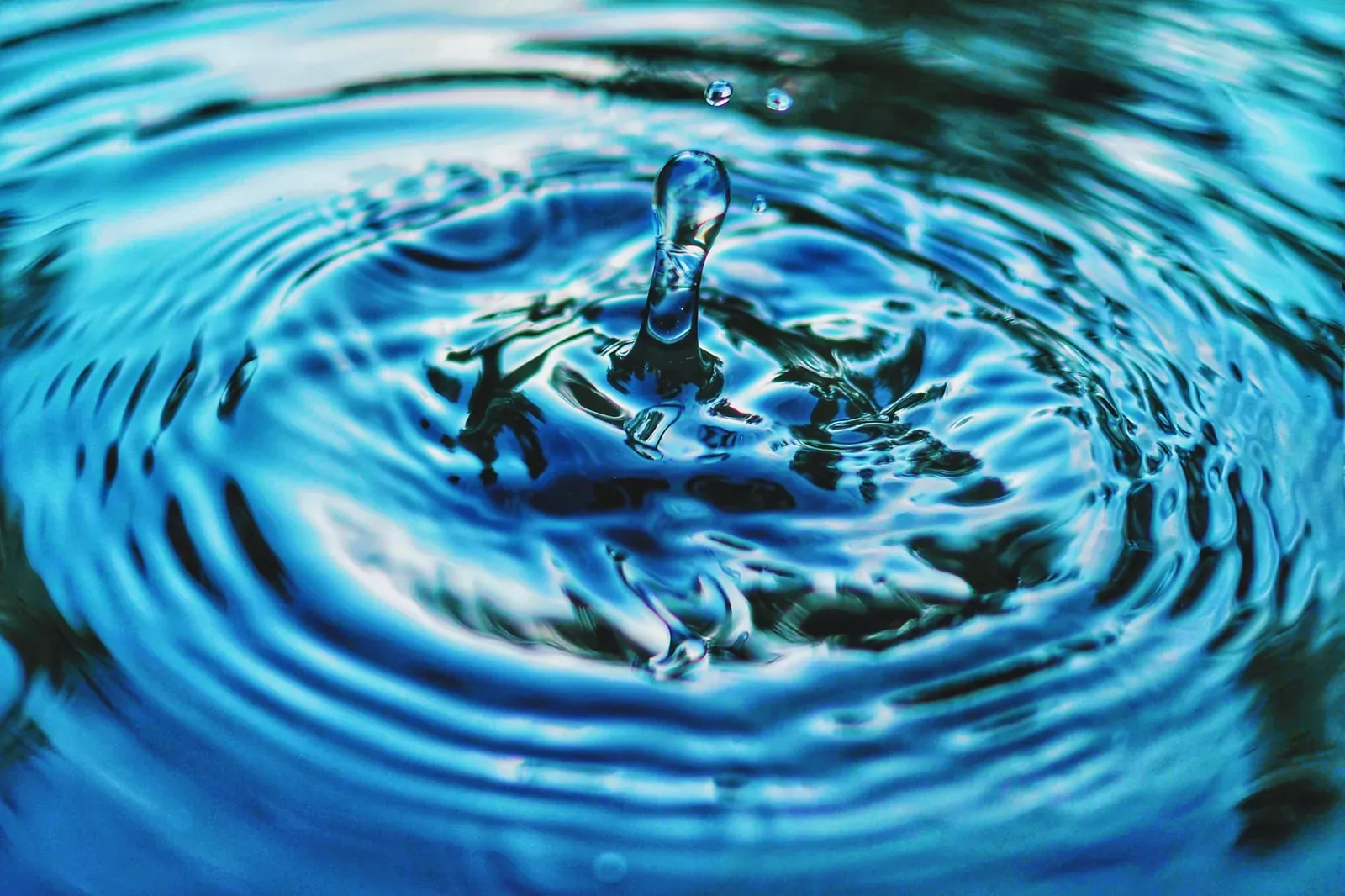 Close-up of a water droplet rippling in blue water